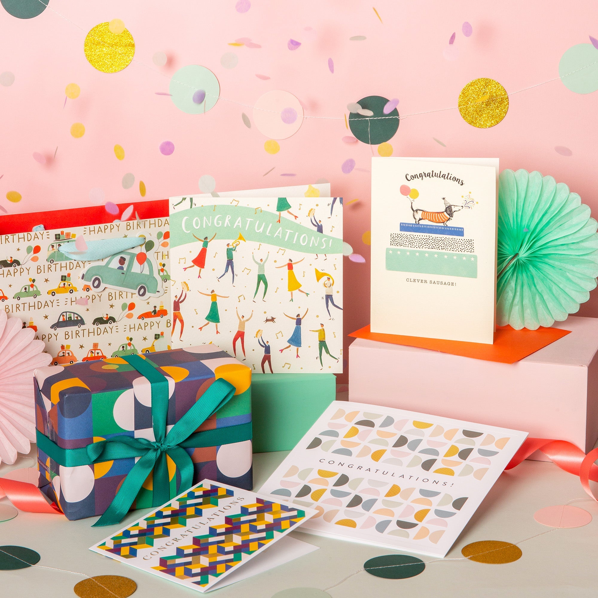 A selection of congratulations cards, bags and presents displayed with confetti.