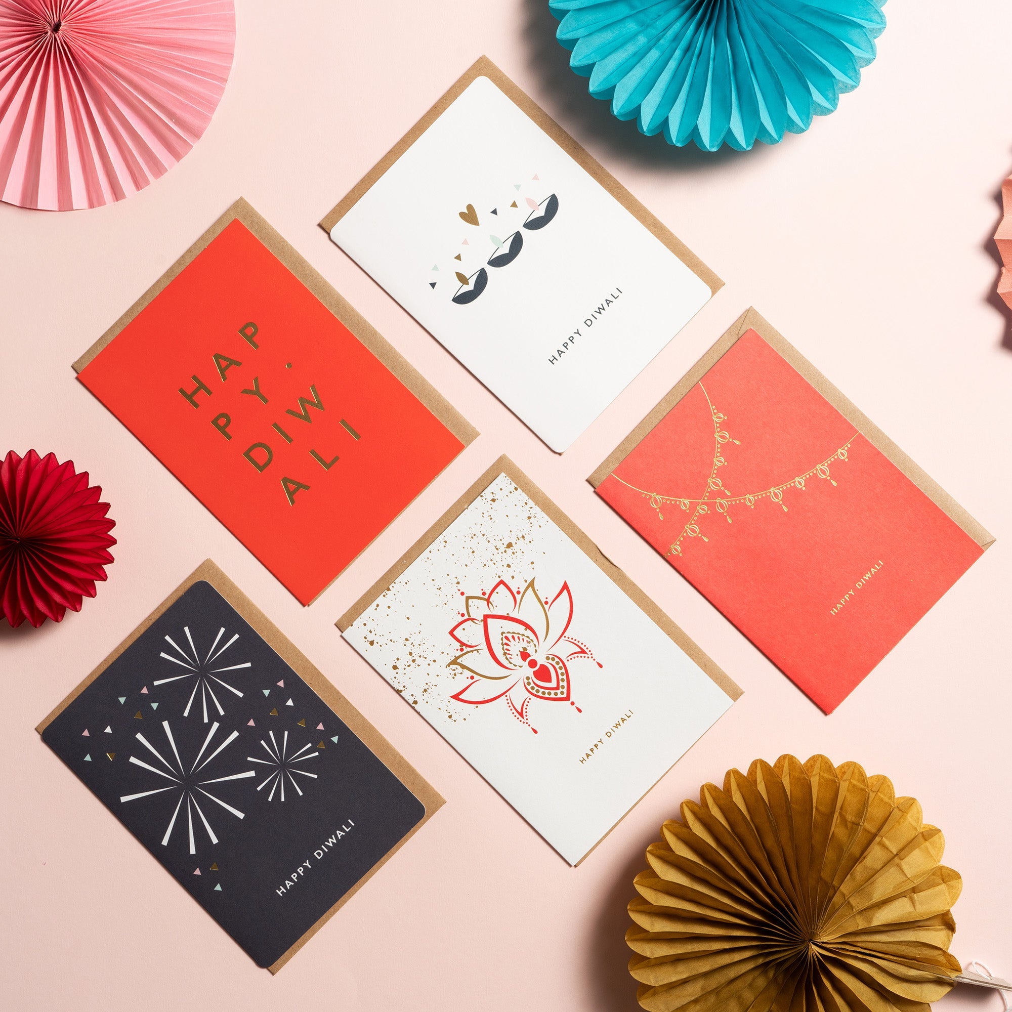 Bright and bold Diwali cards laid out on a table with paper decorations.