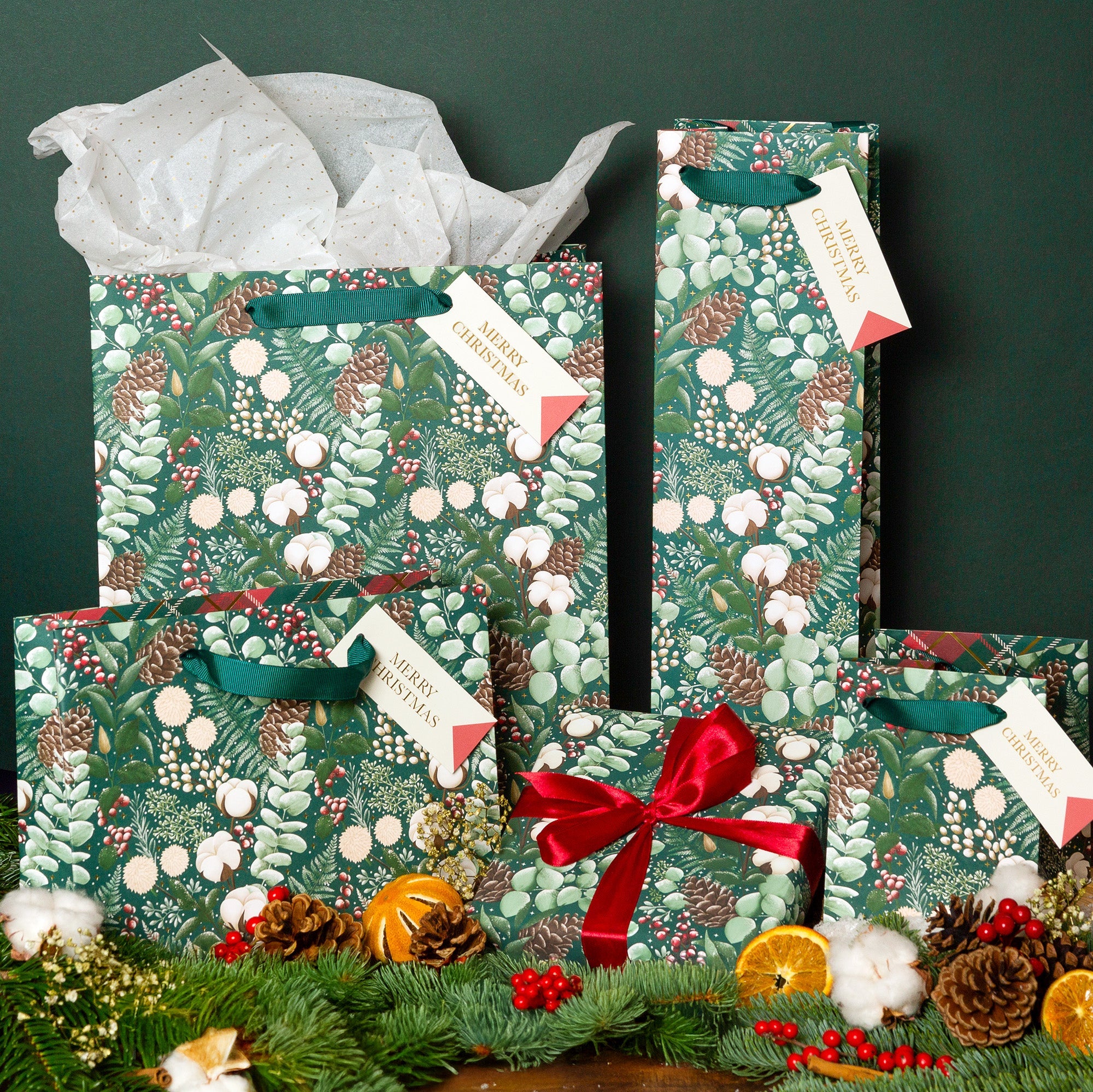 Four festive gift bags filled with Christmas tissue paper.