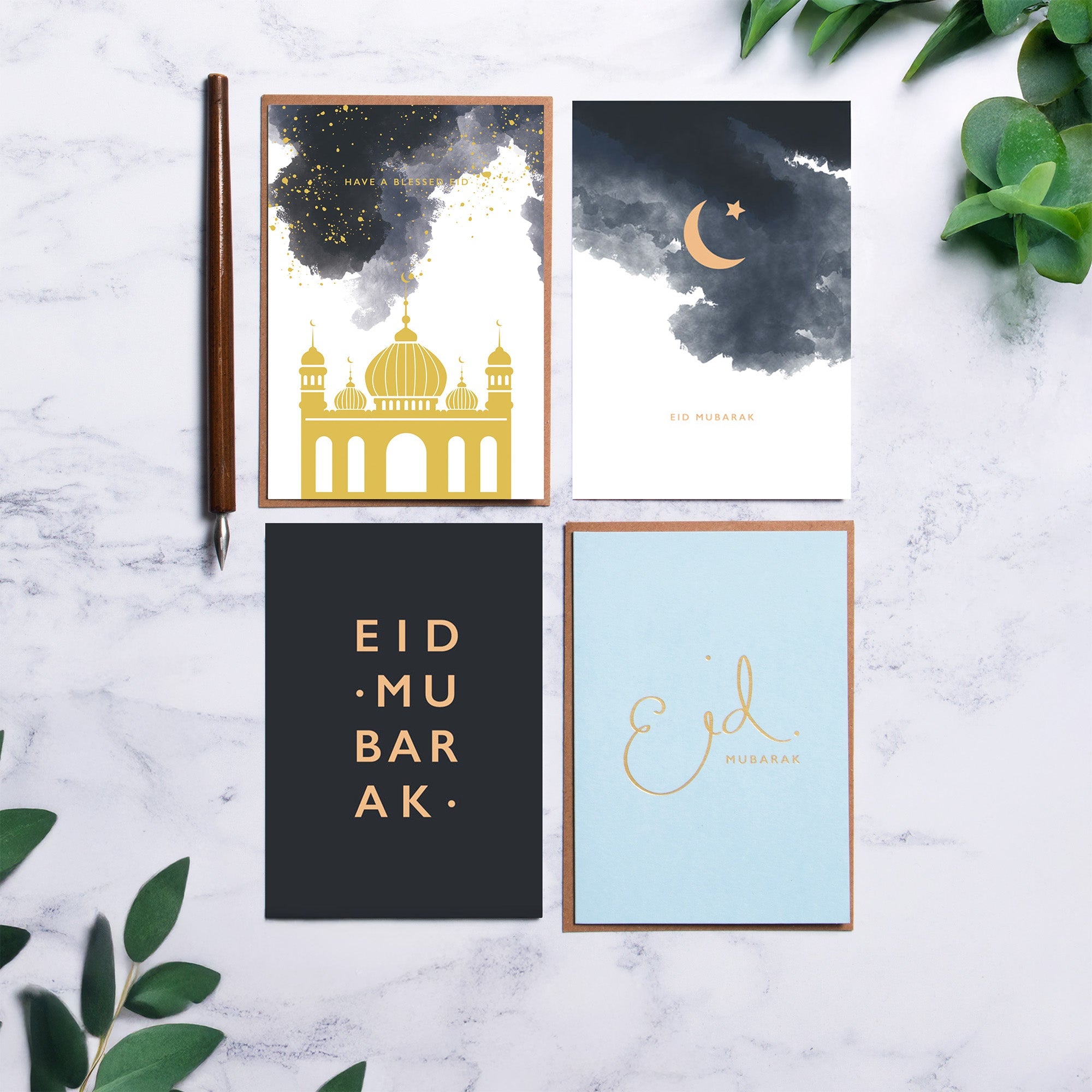 A selection of Eid cards on a marble counter, surrounded by green plants.