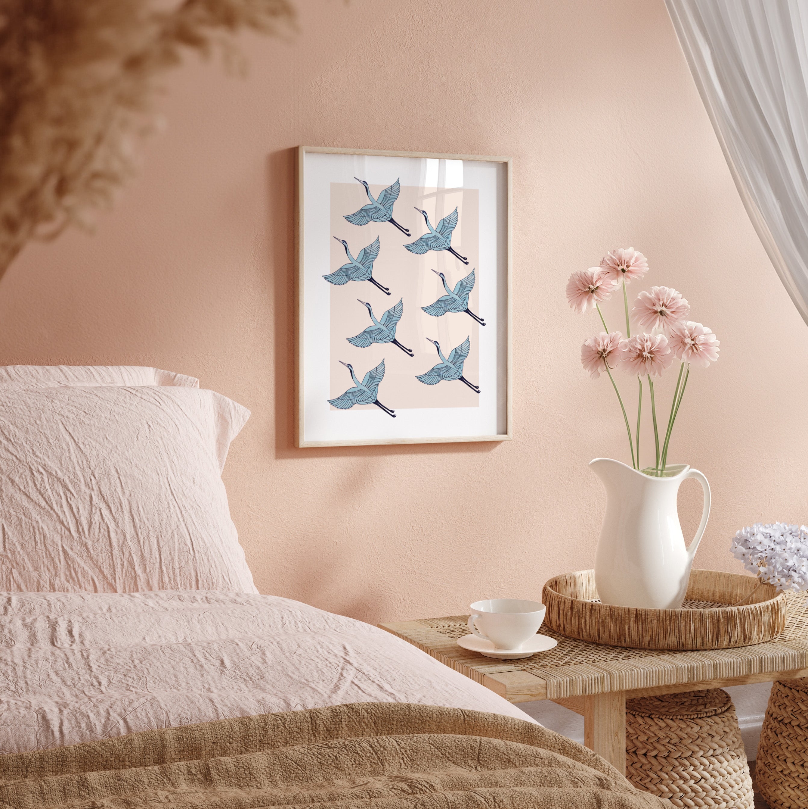 Bedroom with a framed artwork of blue birds, a vase with pink flowers, and a cup on a side table.