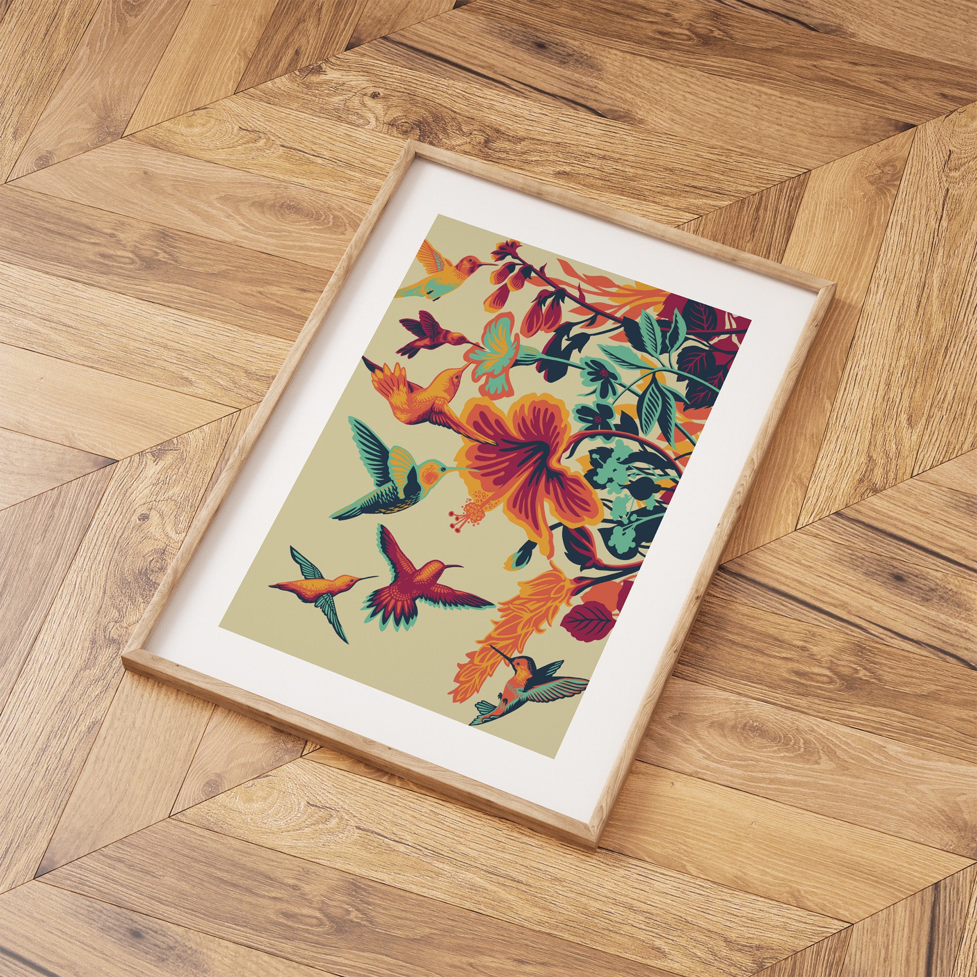 Framed art print featuring brightly coloured hummingbirds hovering above vibrant flowers, laid out on a wooden floor.