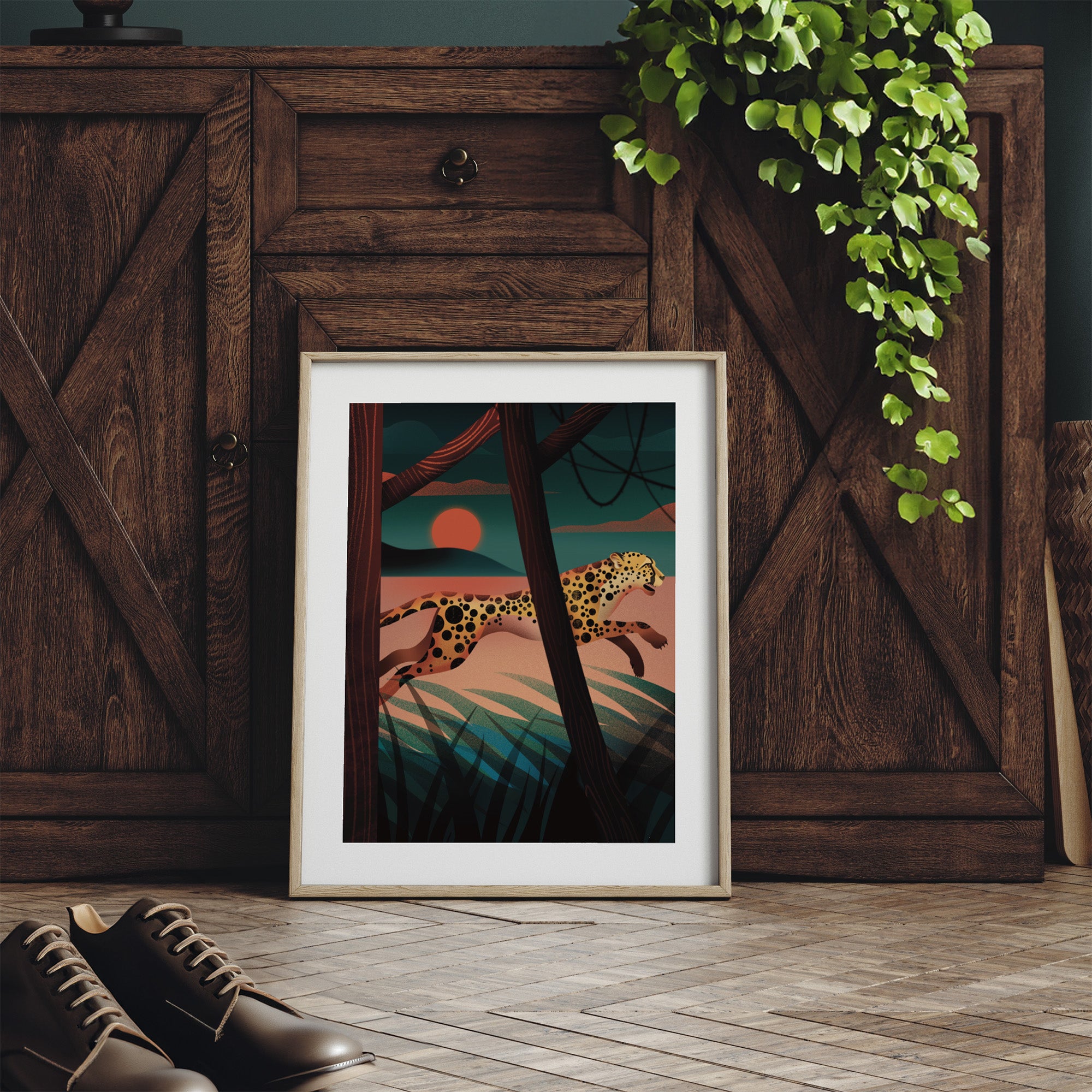Framed vibrant art print featuring a cheetah sprinting through a forest at sunset. Print is leaning against a dresser.