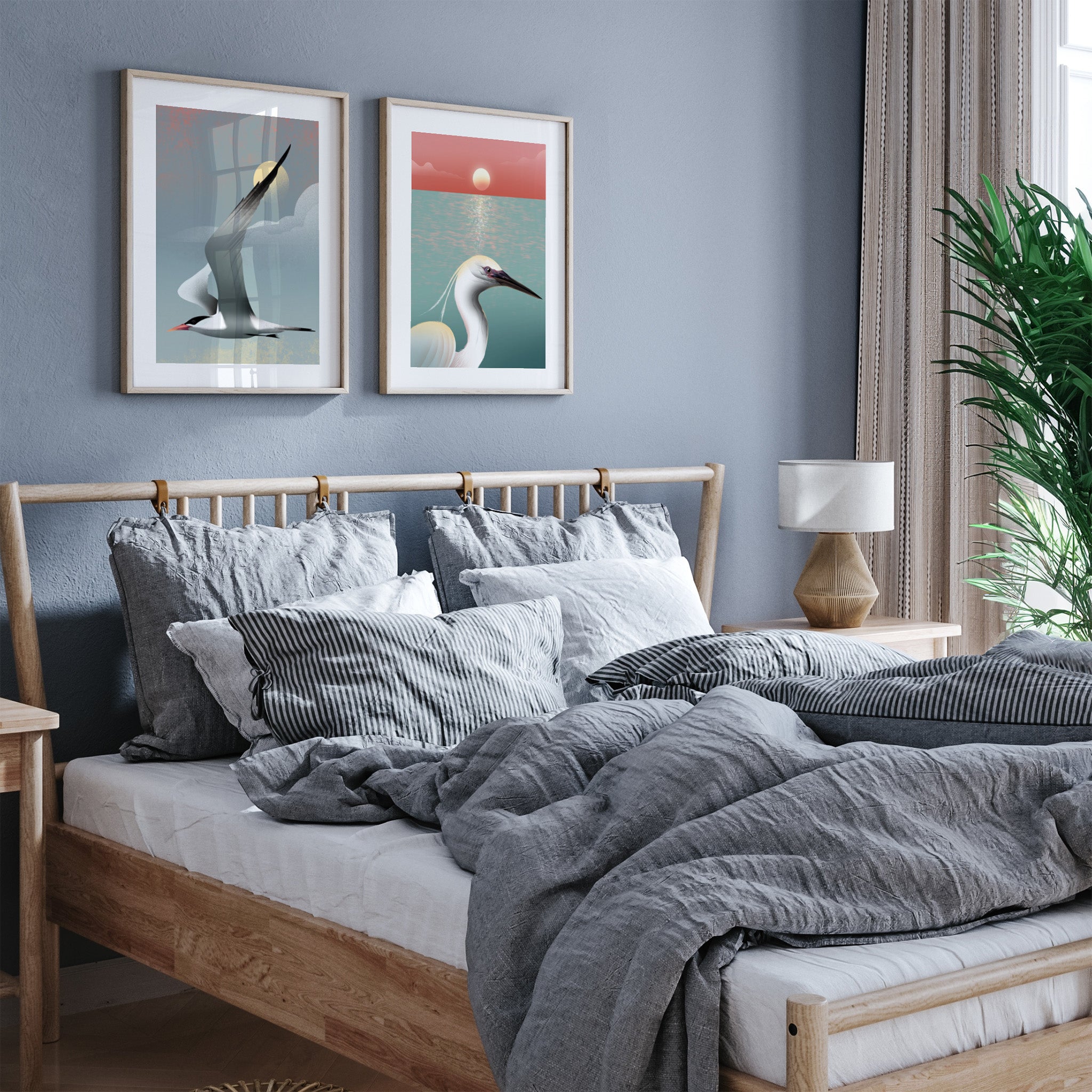 Framed art print featuring a tern flying through a cloudy sky. Another art print hangs next to it, both displayed in a bedroom.