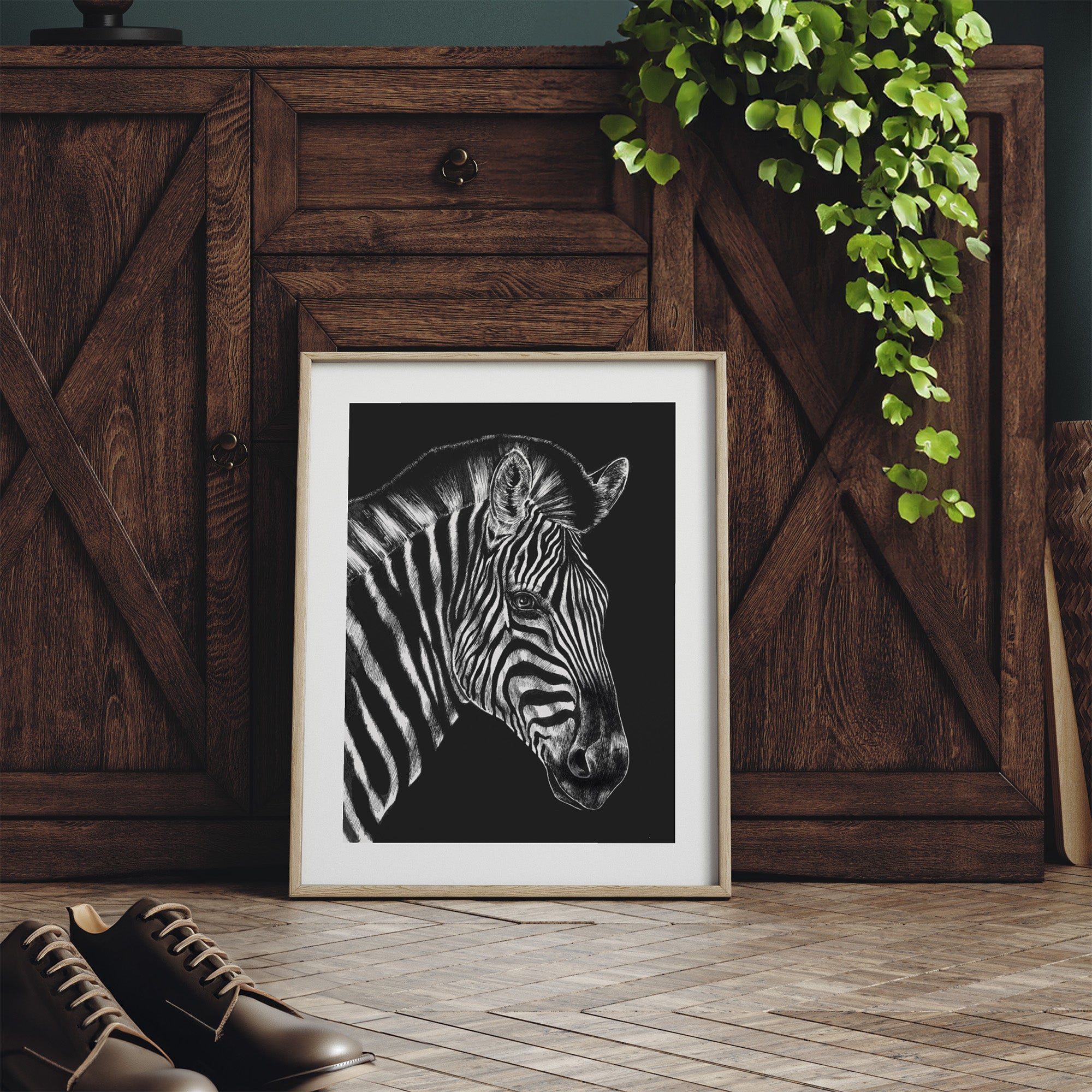 Framed art print featuring a detailed illustration of a zebra, in black and white. Print is leaning on a dresser.