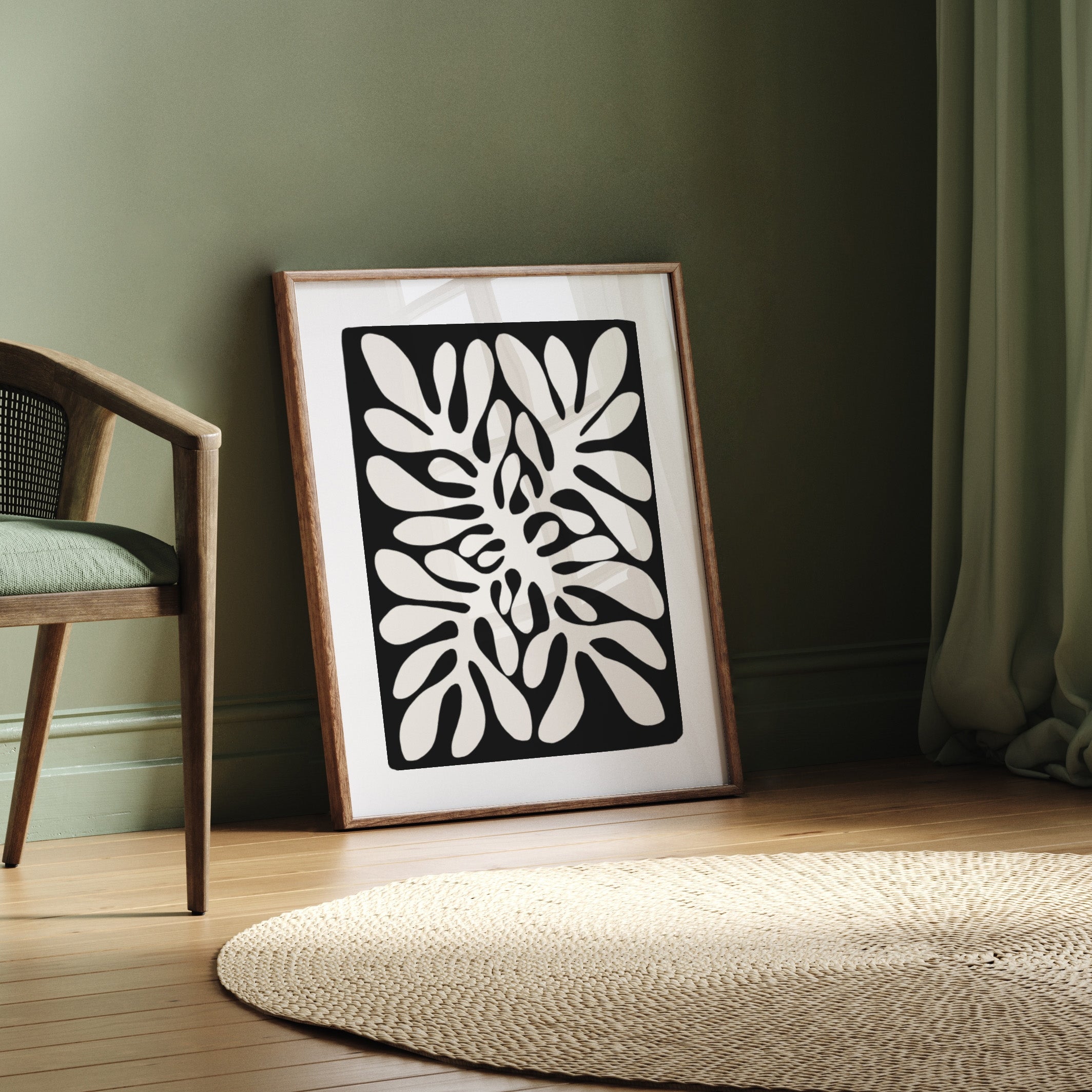 Framed black and white abstract artwork on a wooden floor with a chair and rug.