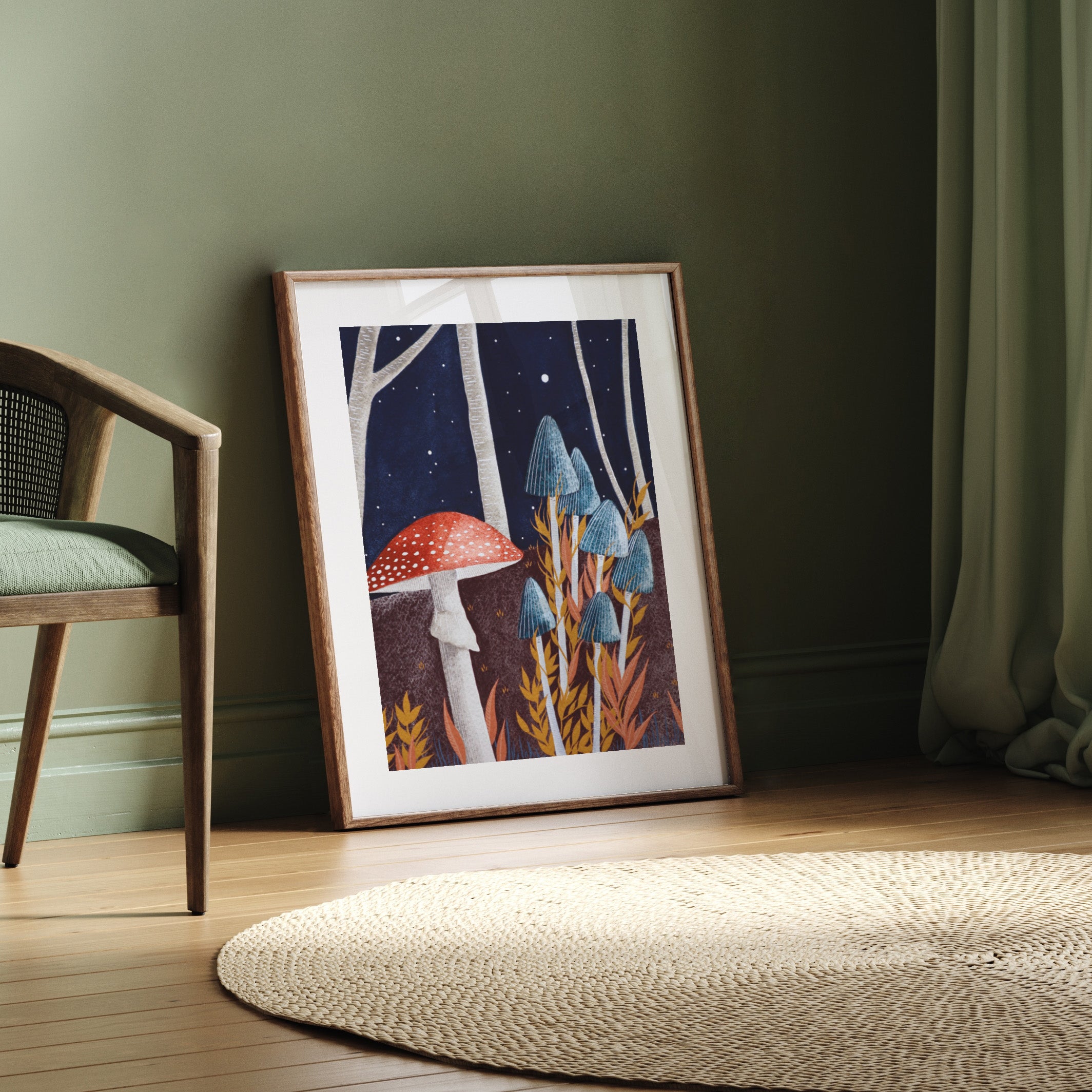 Framed artwork of mushrooms on a wooden floor with a chair and green wall in the background