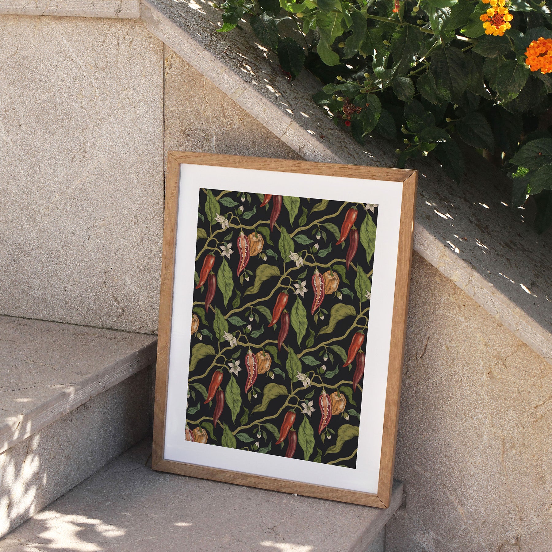 Framed artwork with a chili pepper pattern on a stone ledge.