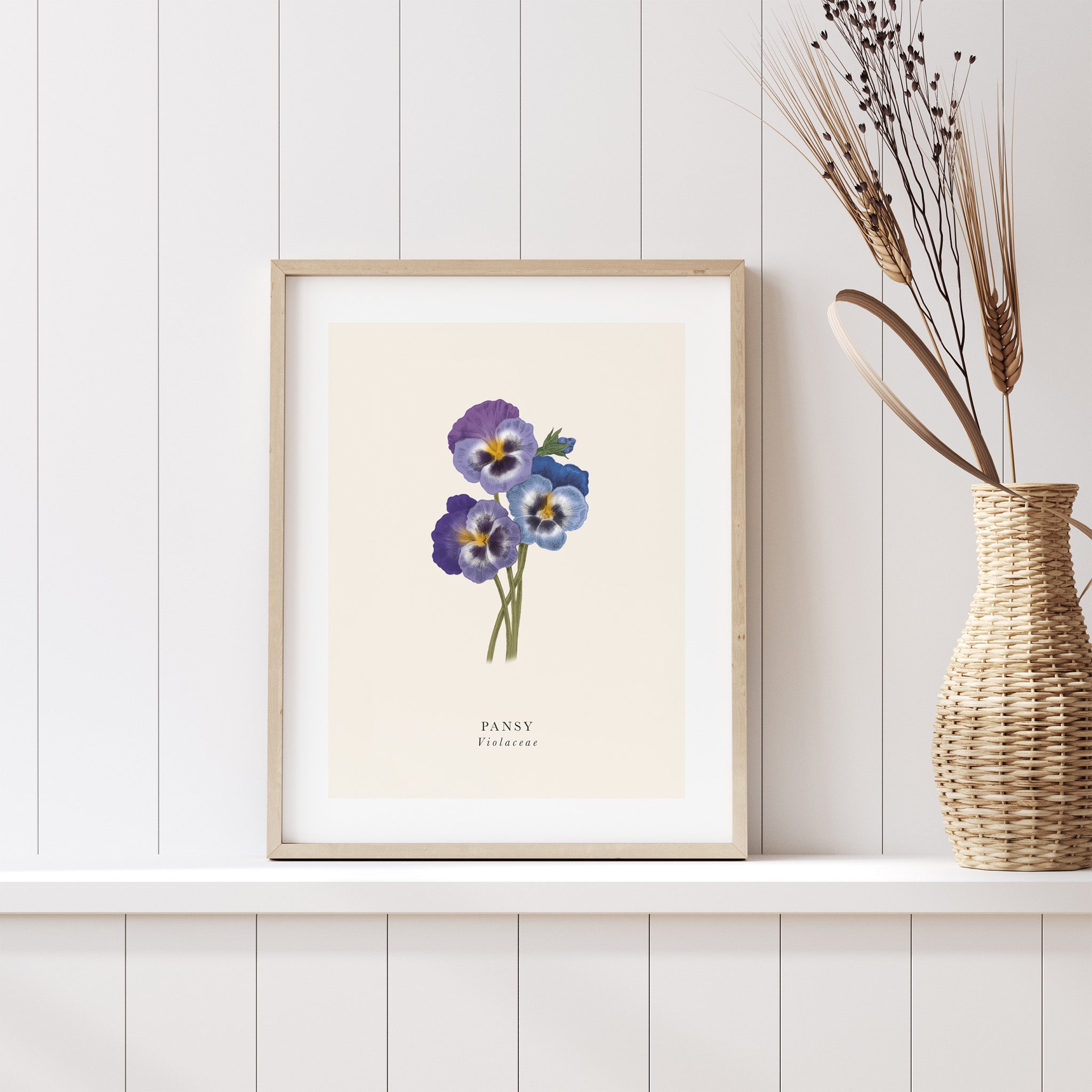 Framed artwork of purple flowers on a white wall with a woven vase.