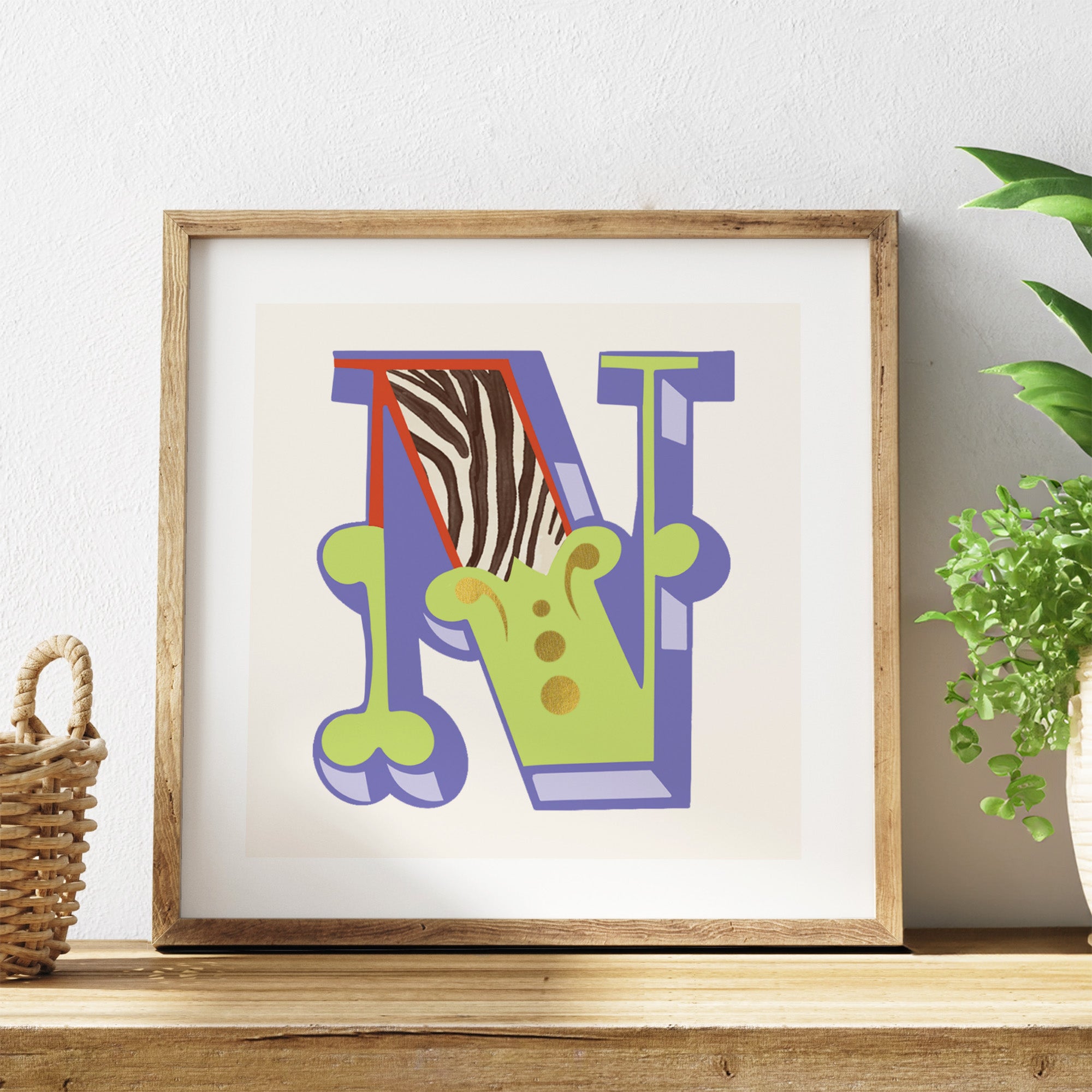 Framed artwork with colourful letter 'N' on a shelf with a plant in the background.