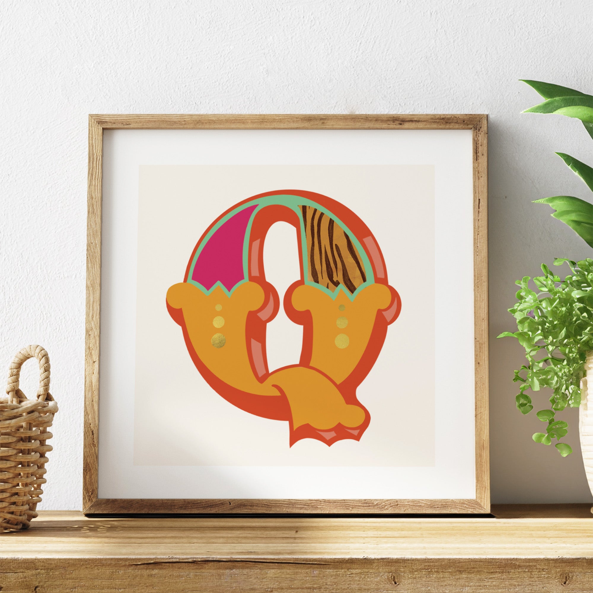 Framed colourful letter 'Q' artwork on a shelf with a plant in the background.