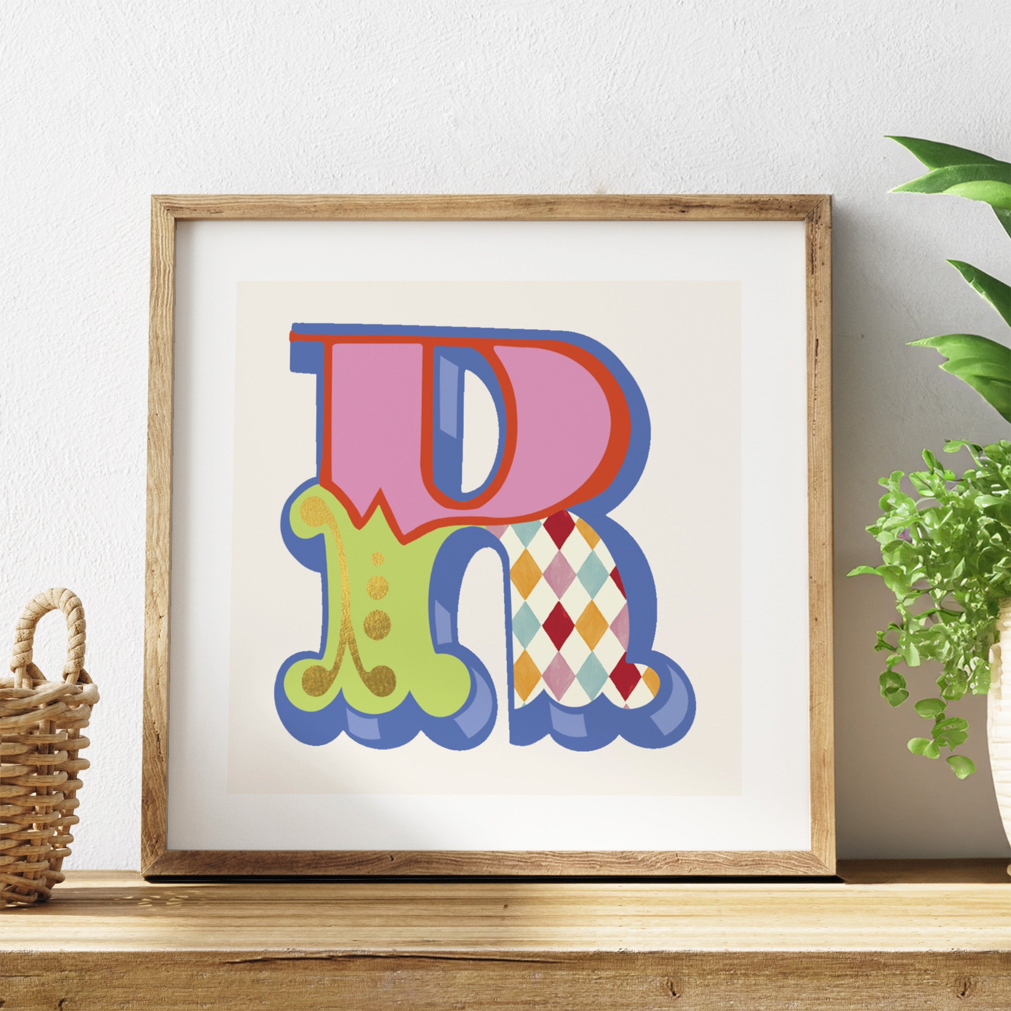 Framed colourful letter 'R' artwork on a shelf with a plant in the background.