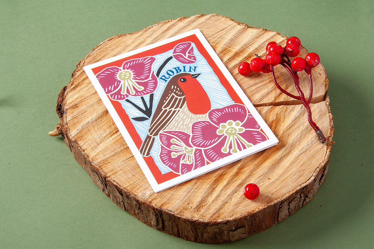 A card is laid on a wooden circle next to some fake berries.