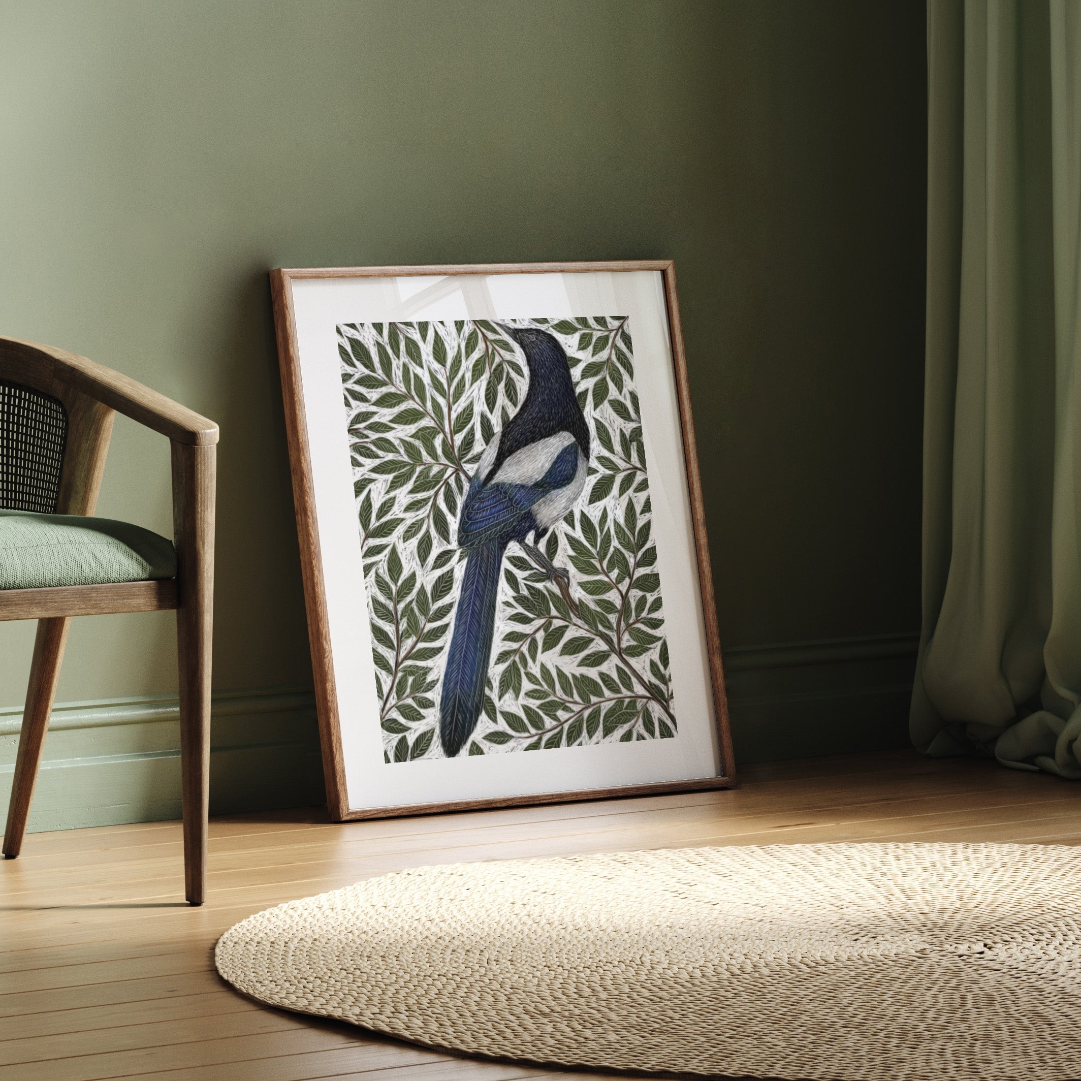 Framed artwork of a bird with leaf patterns on a wall next to a chair.