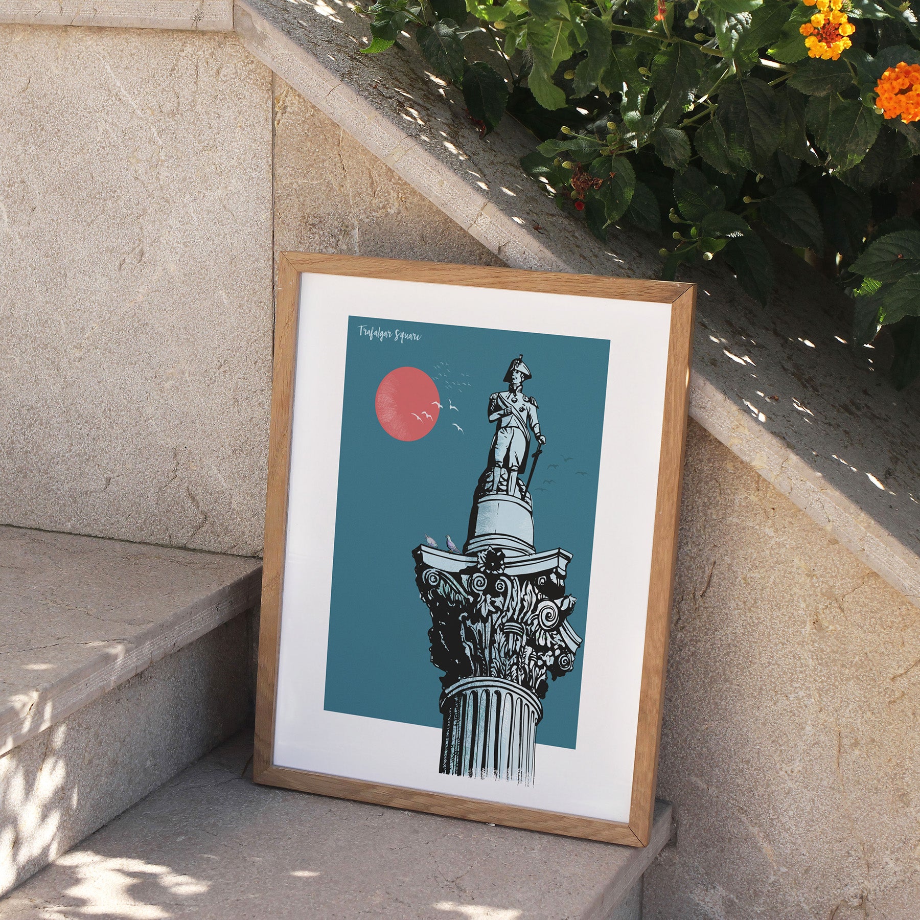 Framed artwork of a statue on a blue background, leaning against a stone wall with plants.