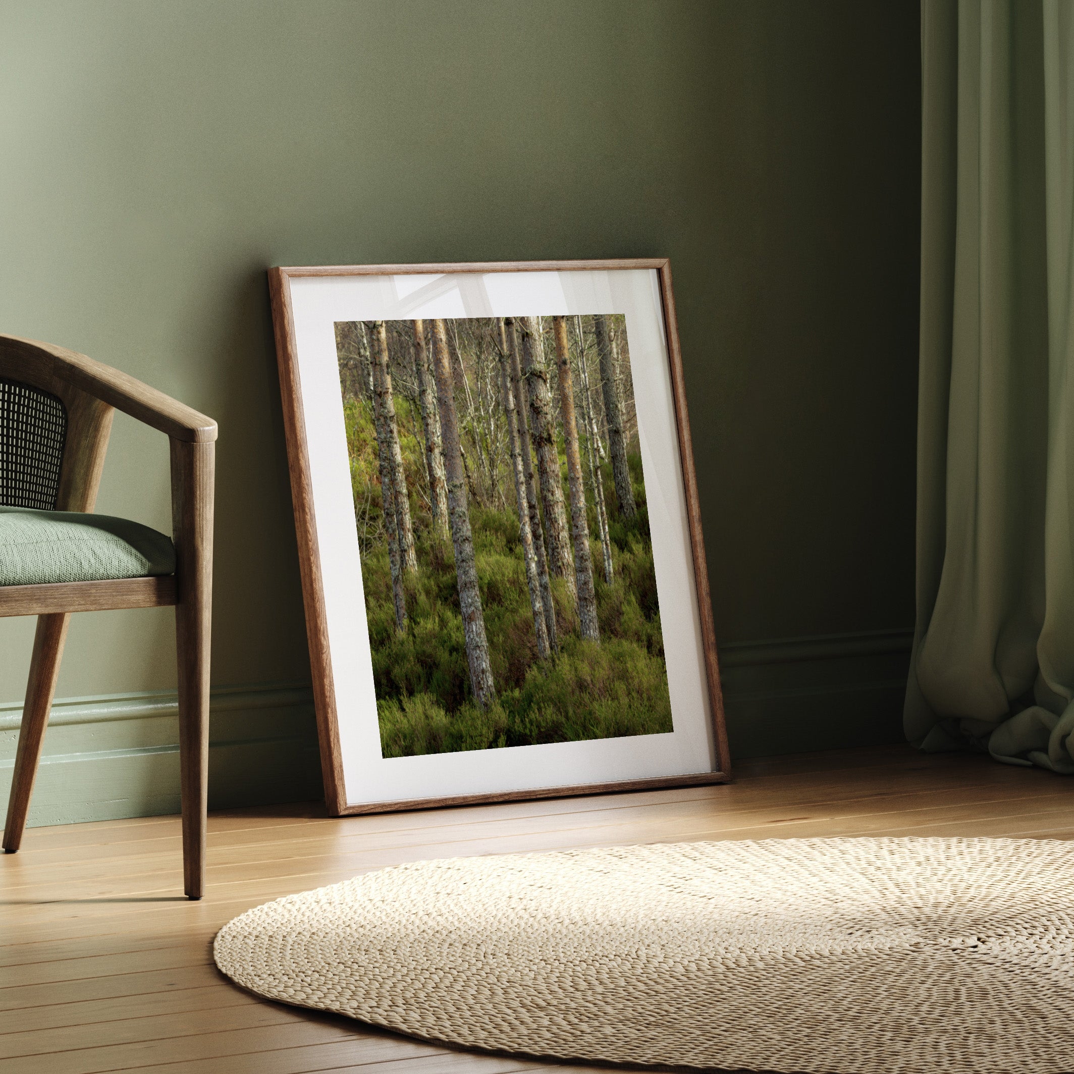 Framed art print featuring a photographic image of a forest of green trees, leaning against a wall.