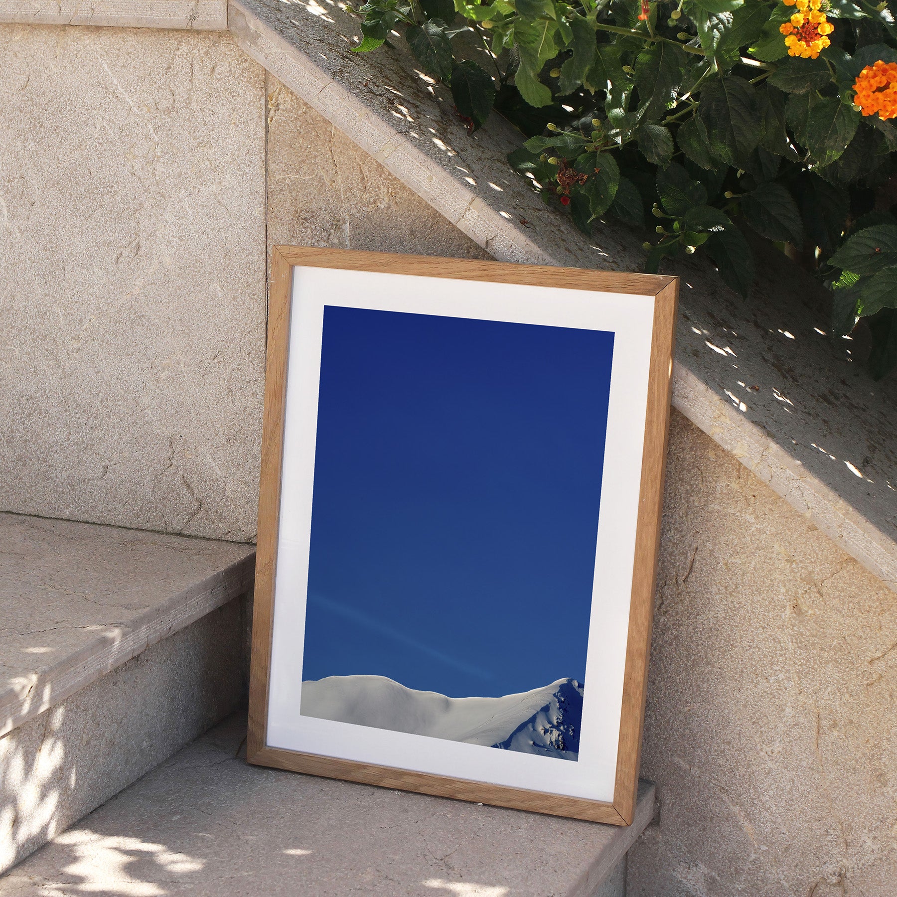 Framed photography art print featuring a snowy peak of Beinn Eighe, perched on stone steps, outside.