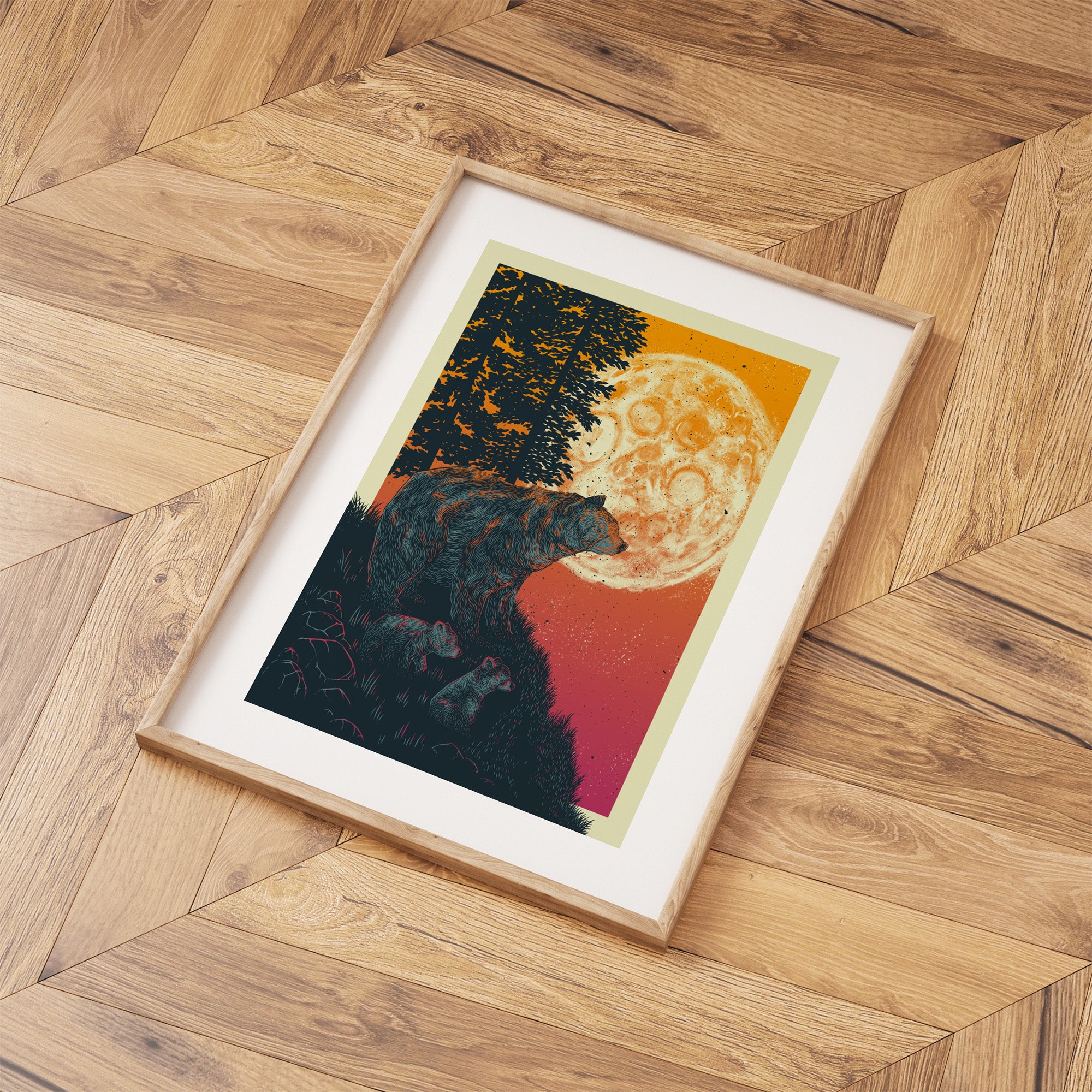 Framed line art print of bears under a luminous red moonrise. Print is laid out on a wooden floor.