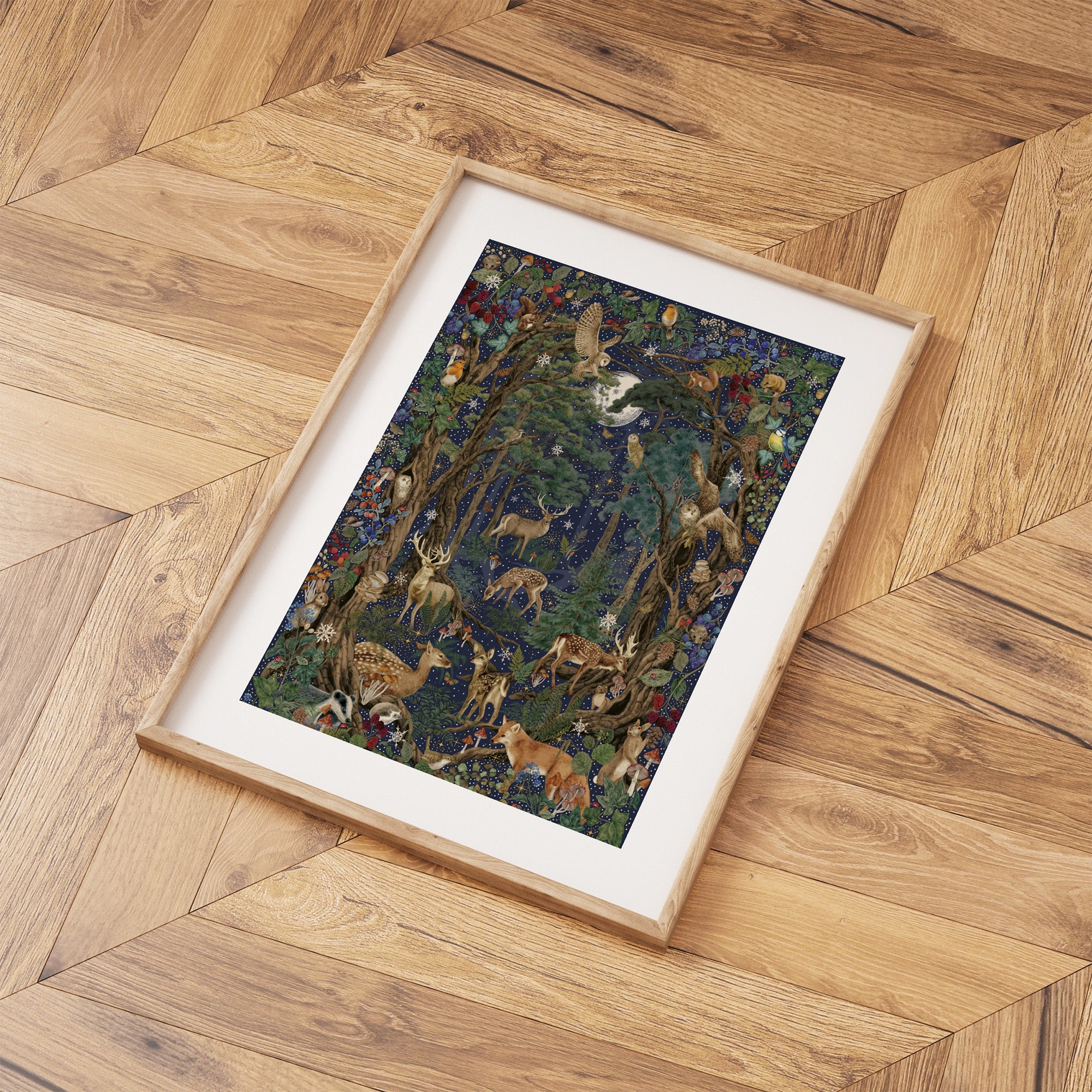 Framed Christmas art print featuring a collection of British wildlife and botanicals in a forest under a star-studded night sky. Print is laid out on a wooden floor.
