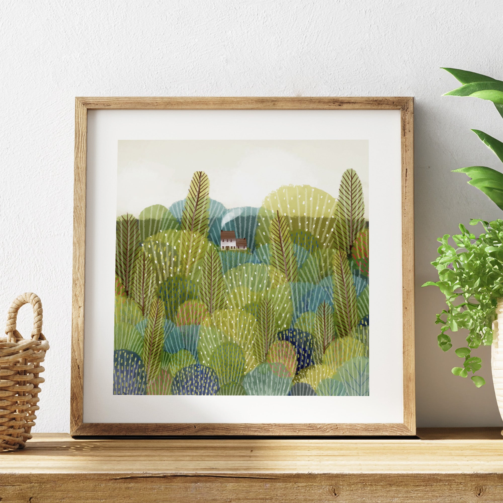 Framed artwork of a landscape with trees and a house on a shelf.