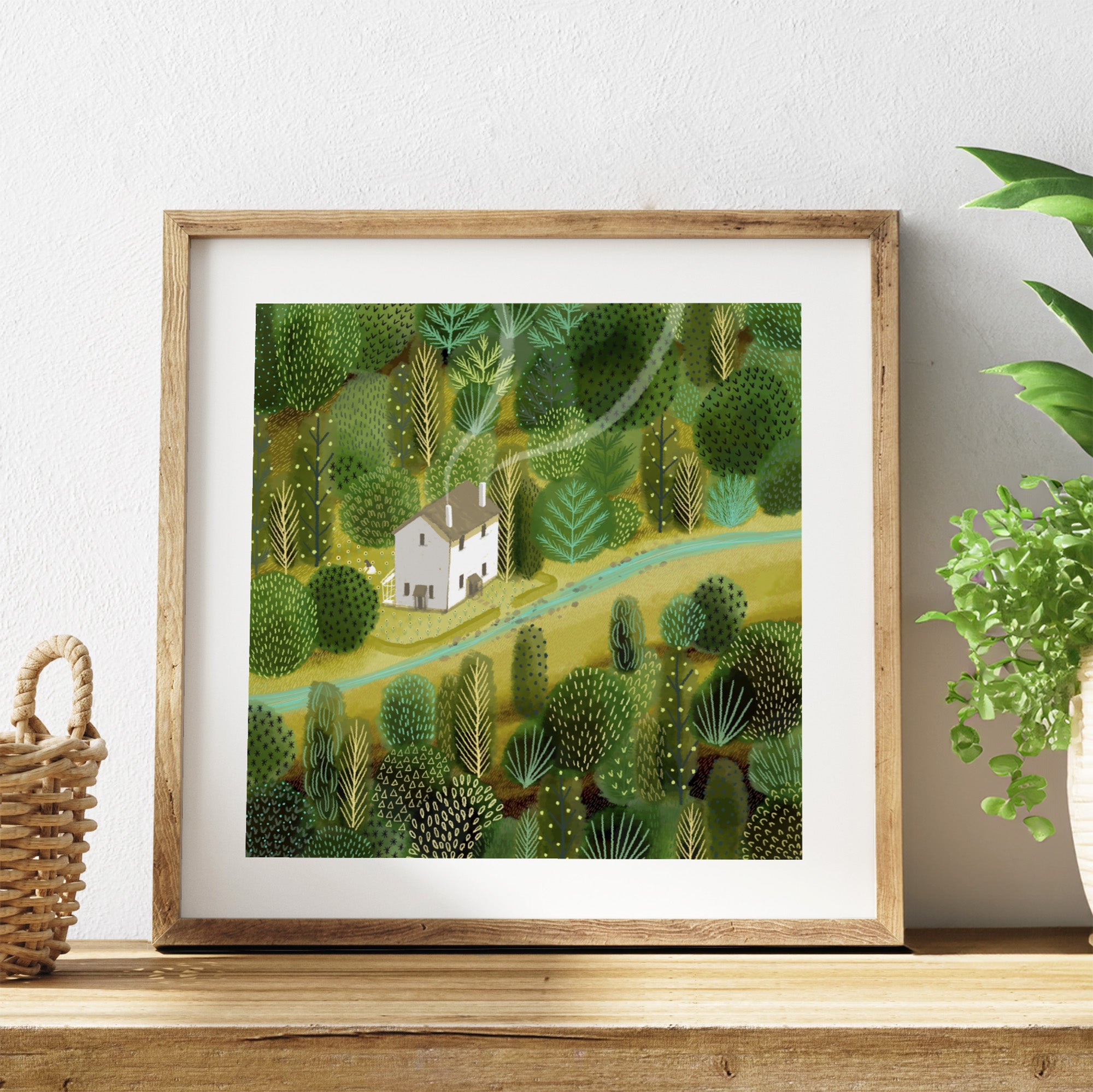 Framed artwork of a green landscape with a house on a wooden shelf.