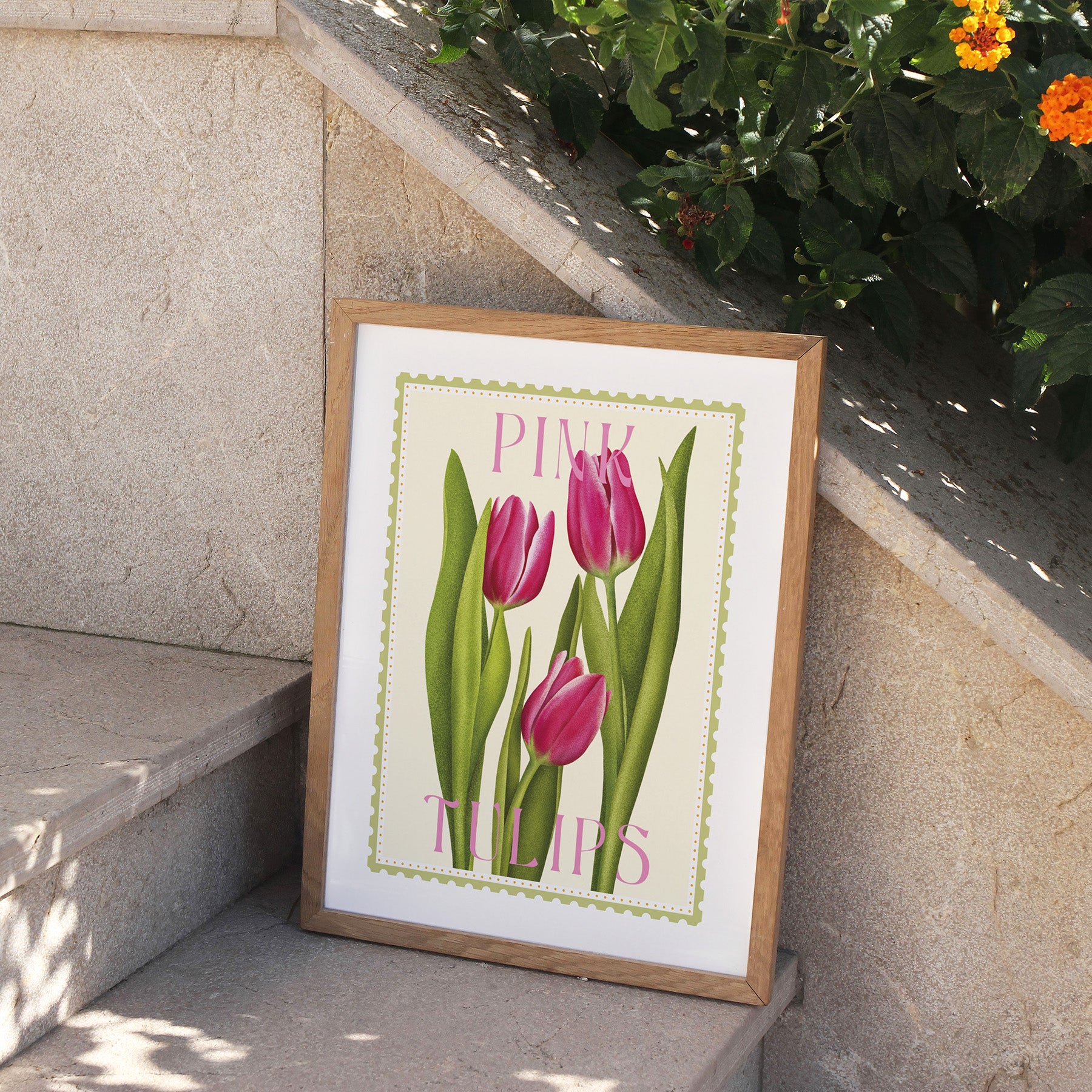 Framed print of pink tulips on a stone ledge with flowers in the background