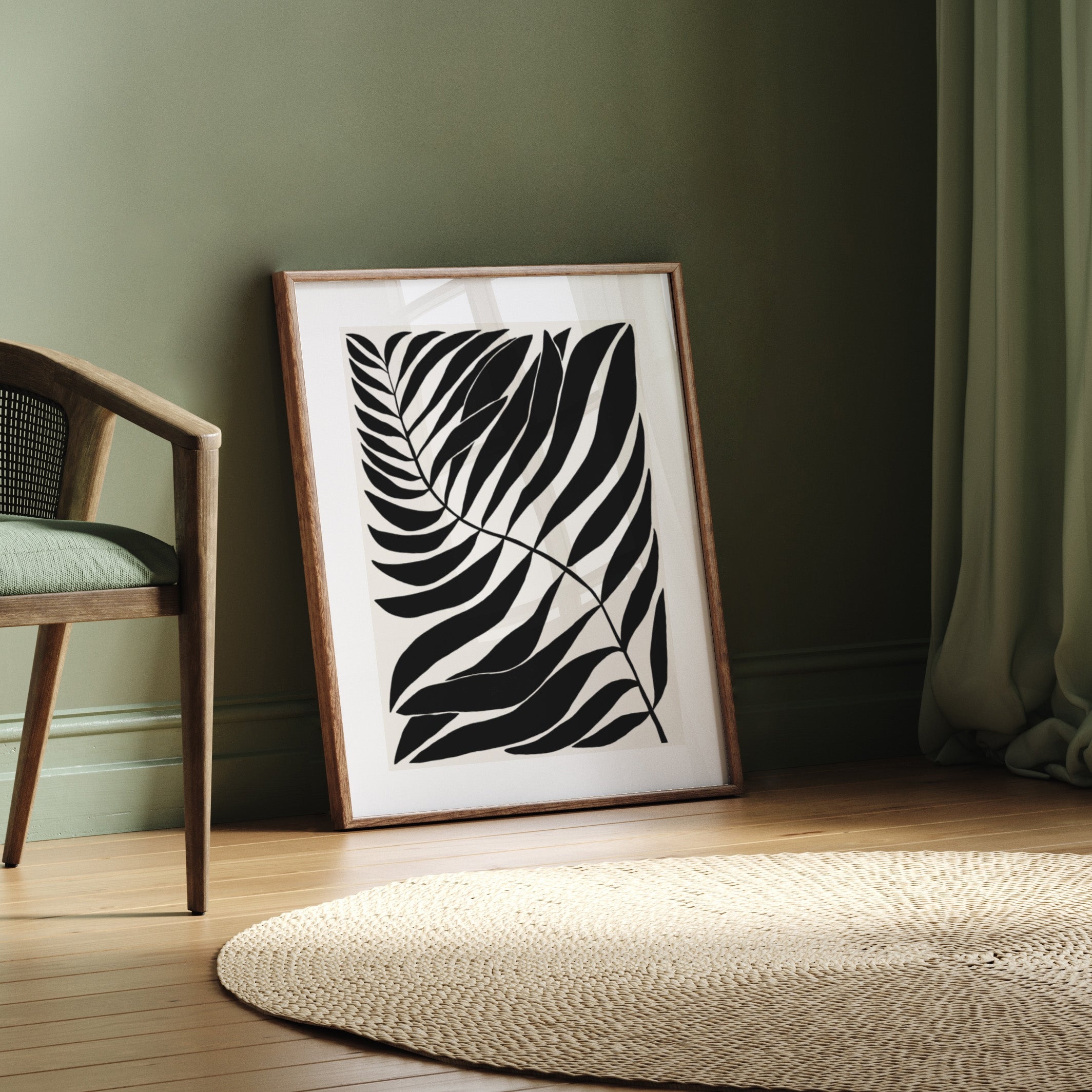 Framed black and white leaf art on a wall next to a chair and rug.