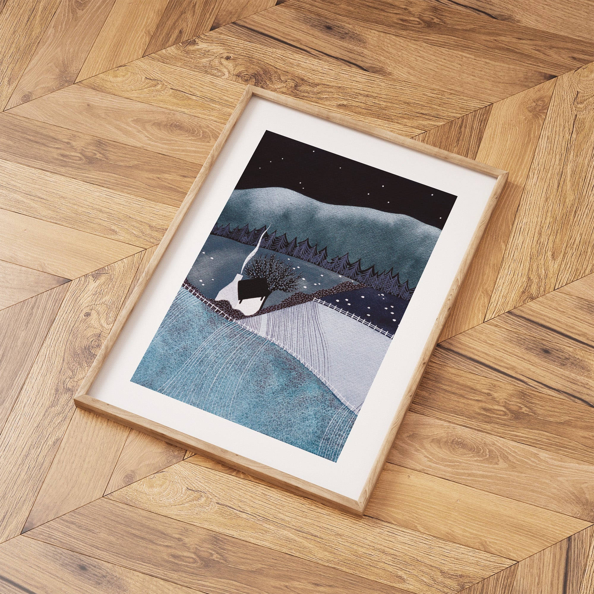 Framed artwork of a snowy landscape with a mountain and trees on a wooden floor.