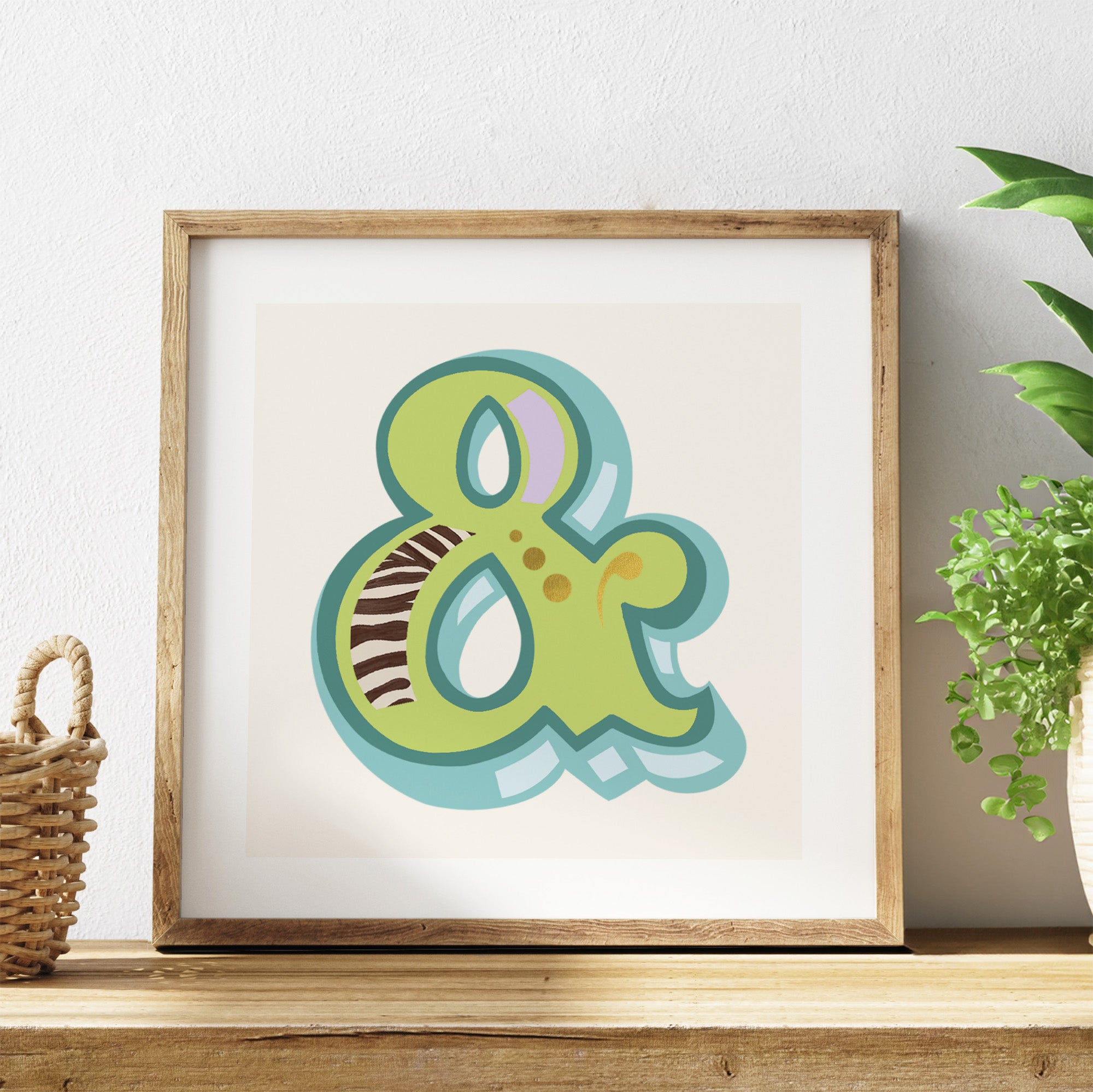 Framed artwork with a colourful ampersand symbol on a white background, placed on a wooden surface.