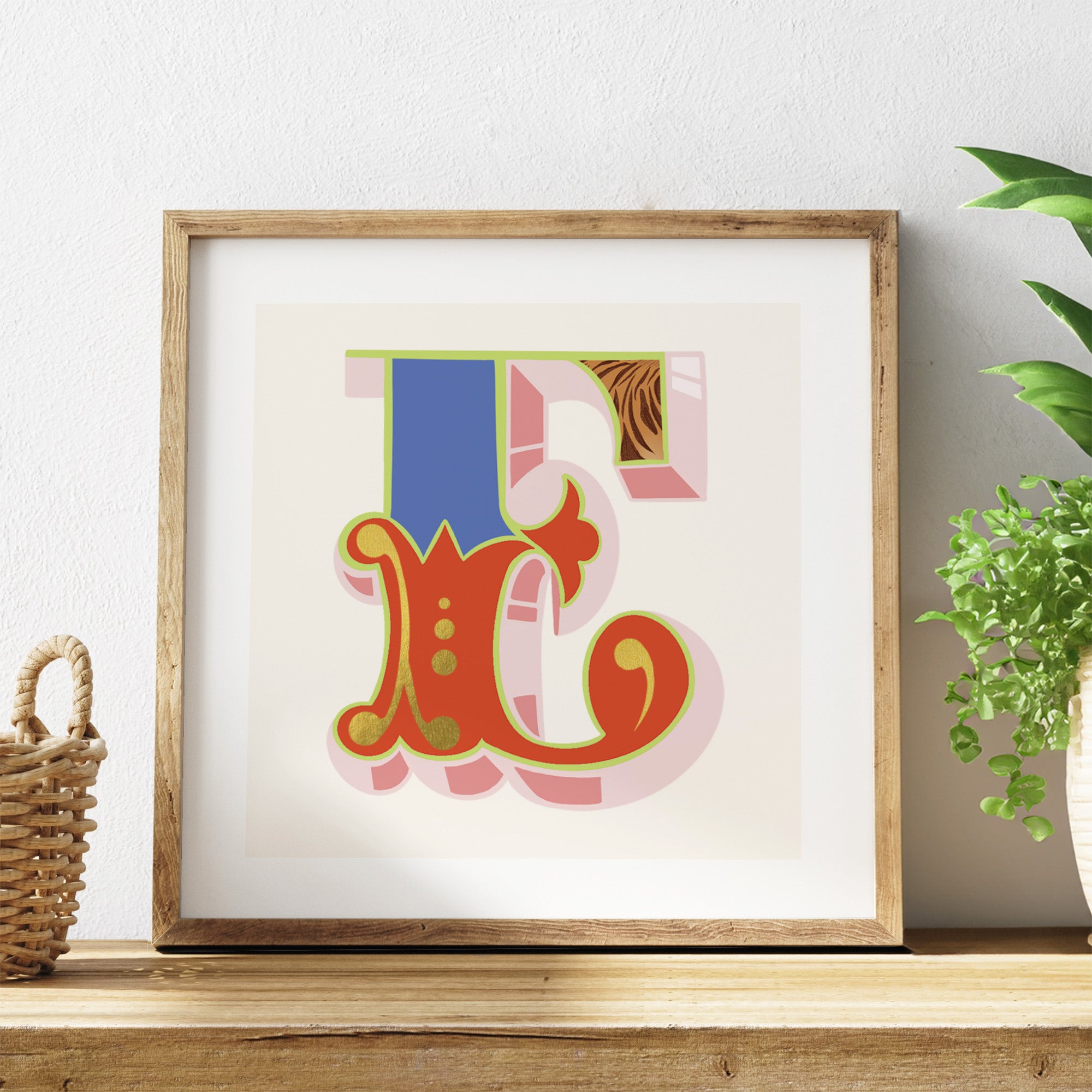 Framed colourful letter 'E' art piece on a shelf with a plant in the background.