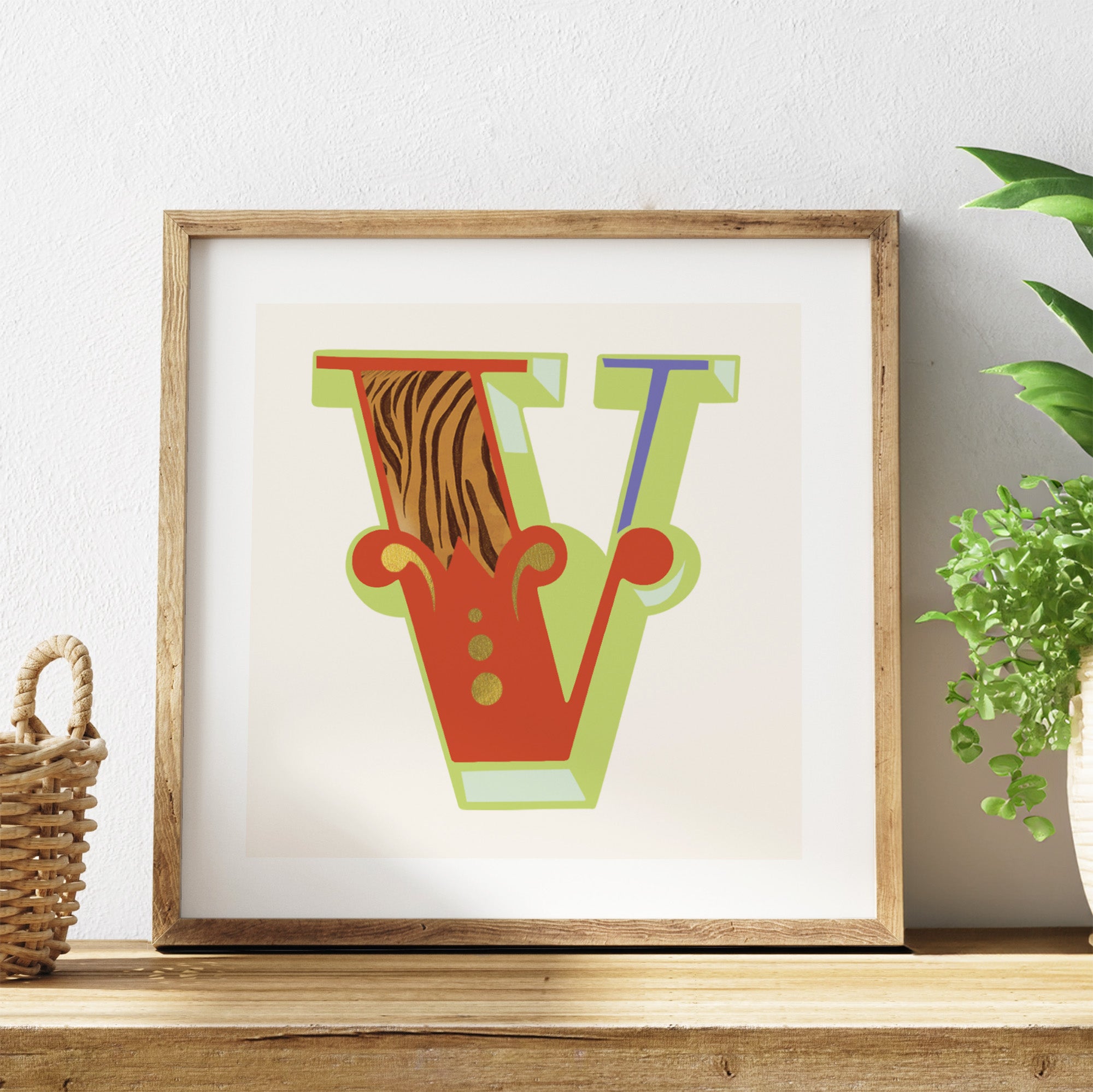 Framed artwork with colourful letters on a shelf with a plant in the background.