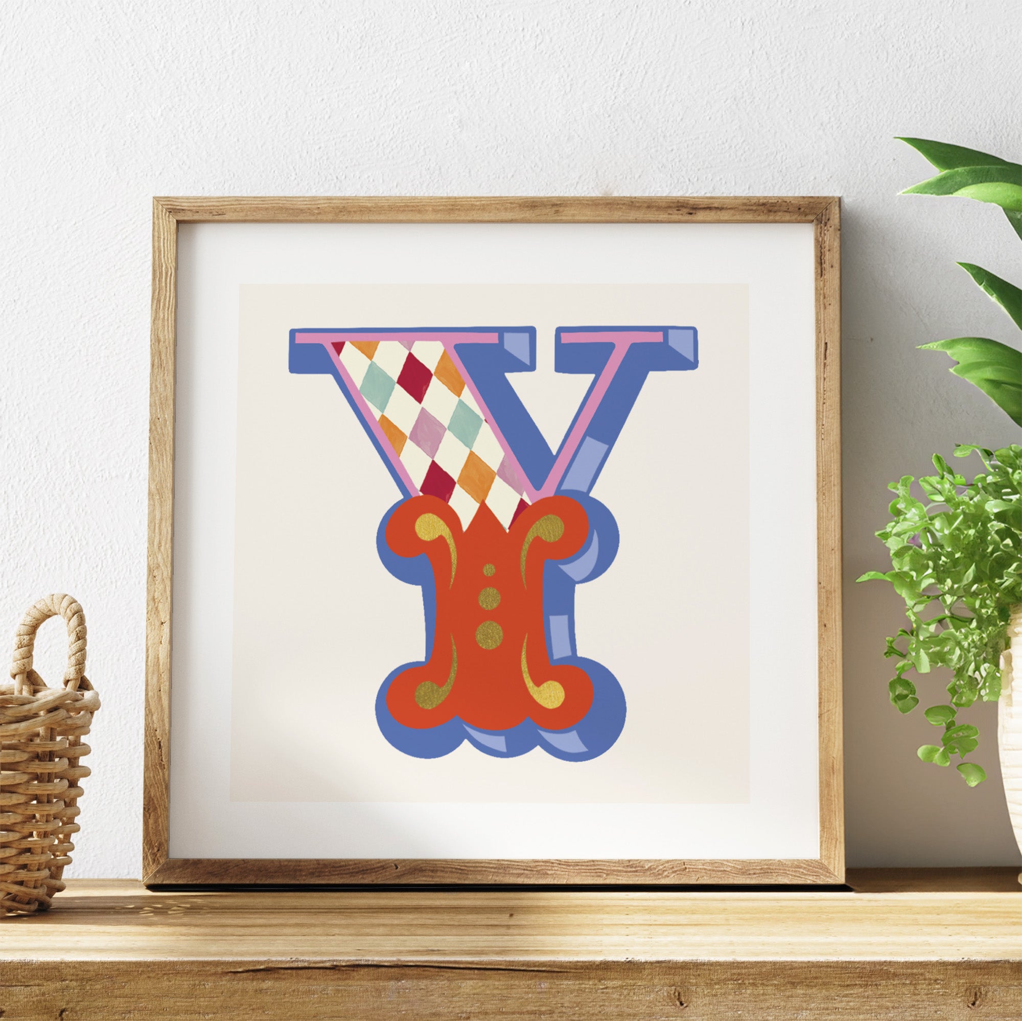 Framed colourful letter 'Y' artwork on a shelf with a plant in the background.